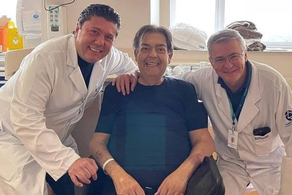 Faustão ao lado de dois médicos. Todos estão sorrindo, simbolizando a alegria da alta de Fausto Silva