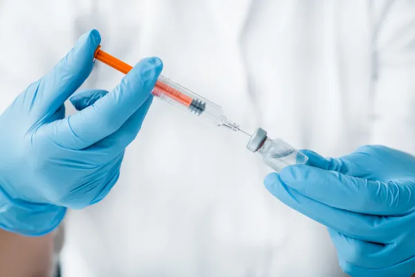 Um enfermeiro, com uma seringa na mão, preparando uma vacina de gripe